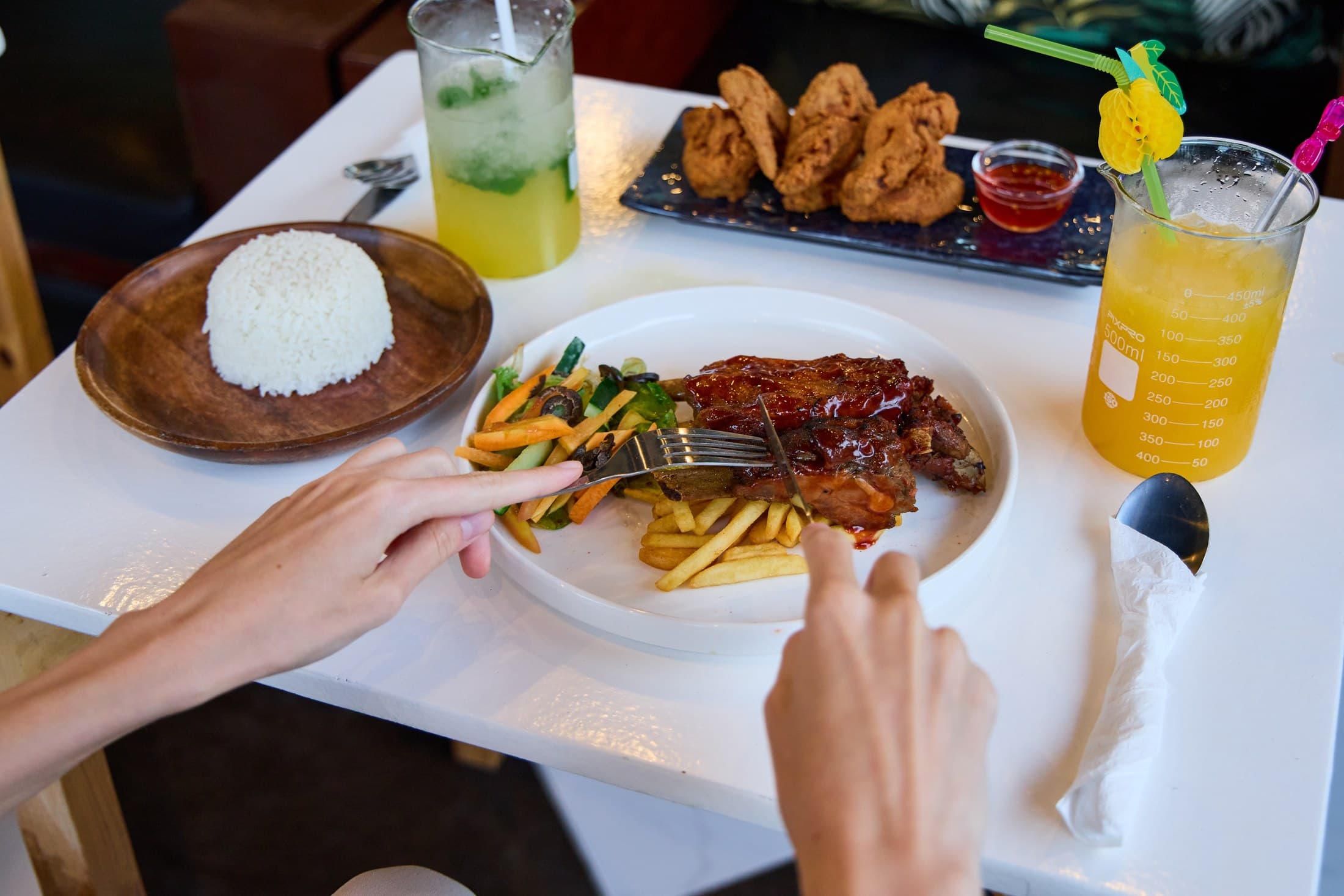 Ribs, rice, fried chicken and tropical drinks on a G Bistro table